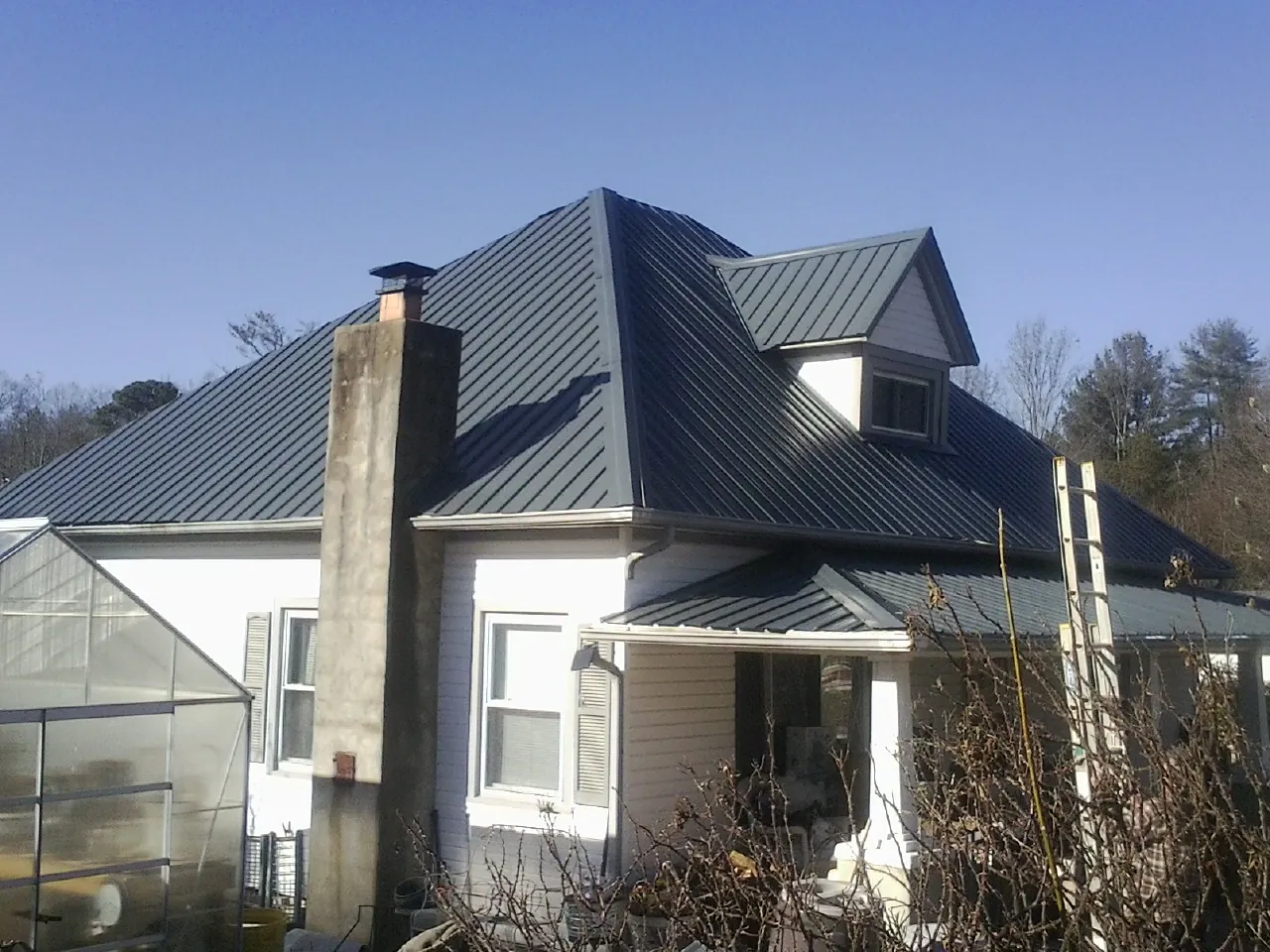 Dark blue standing seam metal roof on a white farmhouse with dormer — Slate & Tile Roof Repair by Roofing Brothers in Mc Kee