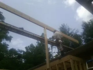 Carpenter setting a ridge beam over a new addition frame — Ice Dam Removal by Roofing Brothers in Mc Kee