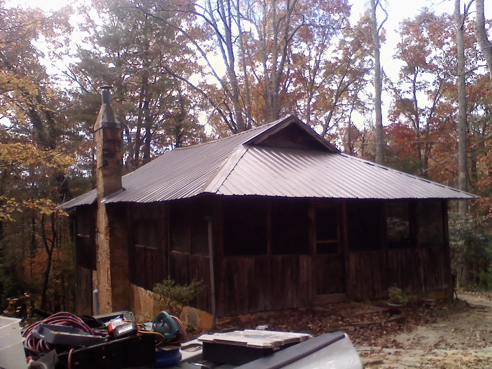 Brown metal hip roof on an old cabin with a stone chimney in Mc Kee