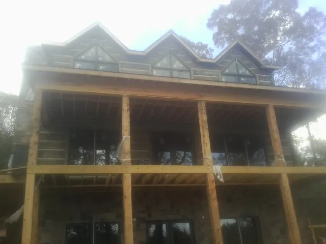 Dormers and porch framing on a large log home under construction — Roof Coating work by our crew in Mc Kee