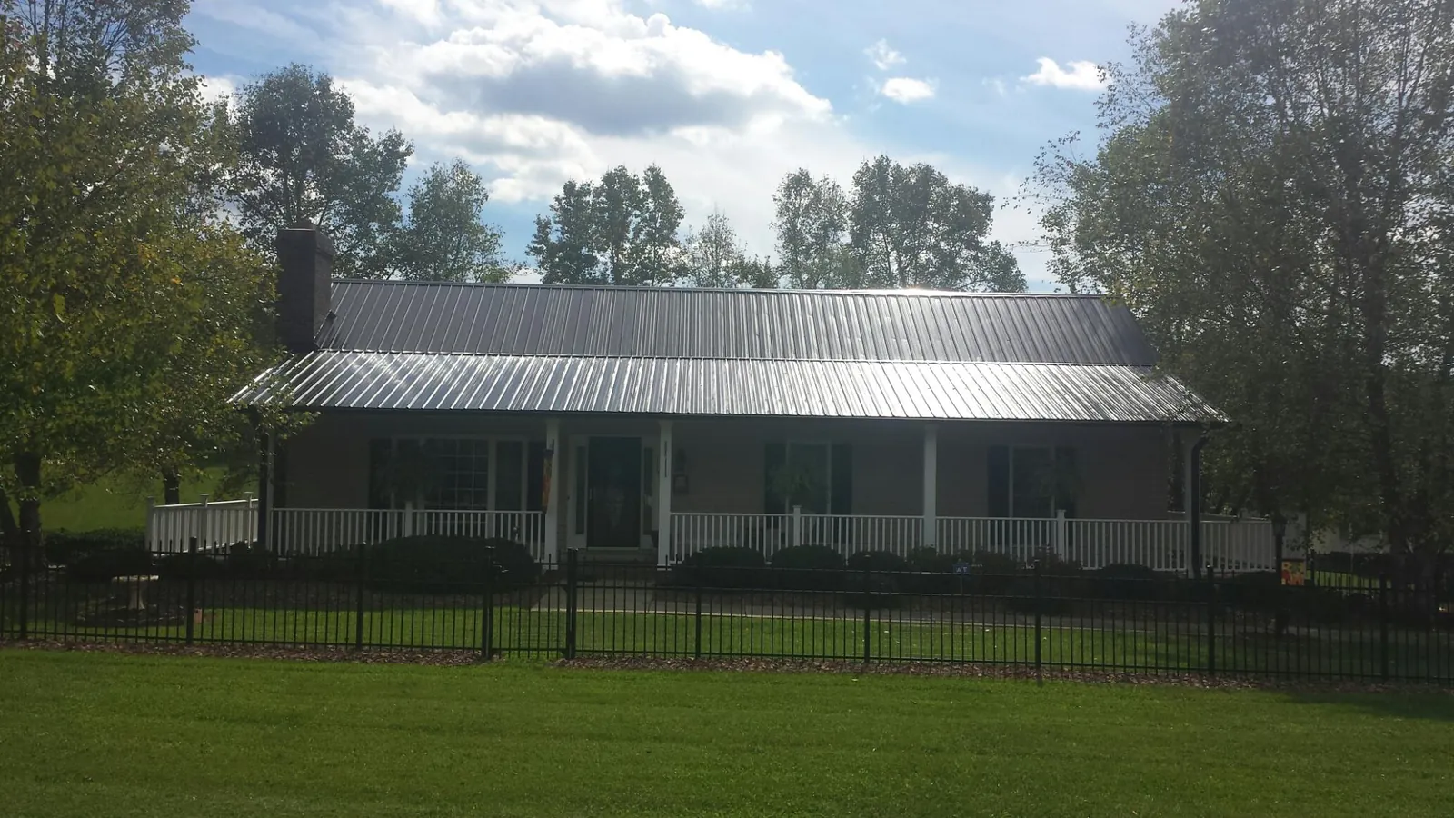 Gray metal roof on a brick ranch with a full width front porch — Gutter Guard Installation work by our crew in Mc Kee