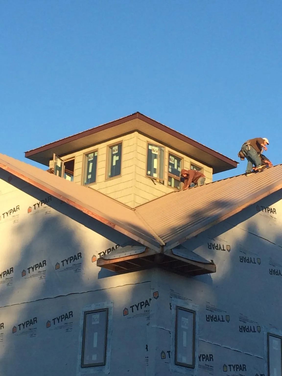 Roofers working around a rooftop cupola on a new metal roof at sunset — Roof Waterproofing in Mc Kee by Roofing Brothers